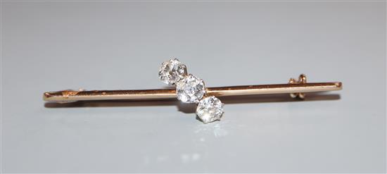 A yellow metal and three stone diamond crossover bar brooch, 52mm.